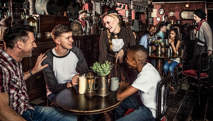Guests enjoying drinks at a themed tavern as part of the London Dungeon premium package.