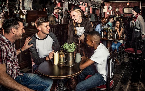 Guests enjoying drinks at a themed tavern as part of the London Dungeon premium package.