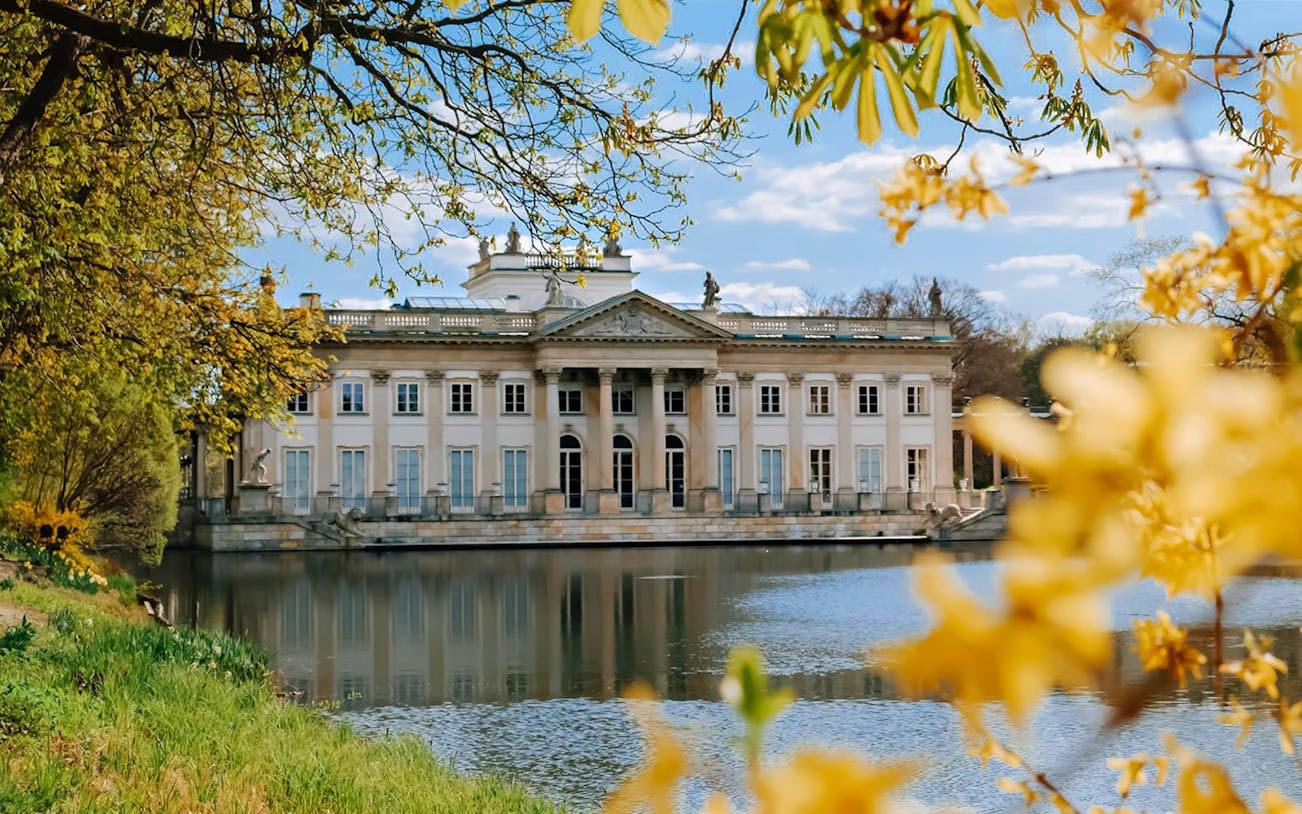 Lazienki Palace in Warsaw with lake and spring foliage, part of Private Guided Warsaw City Tour by Car.