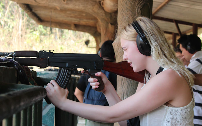 Visitor experiencing shooting range at Cu Chi Tunnels, Vietnam, during VIP speed boat tour.