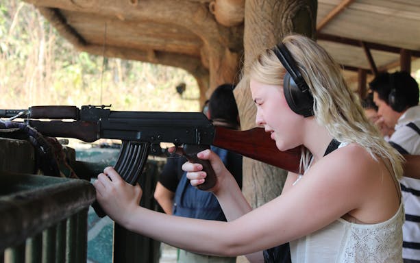 Visitor experiencing shooting range at Cu Chi Tunnels, Vietnam, during VIP speed boat tour.