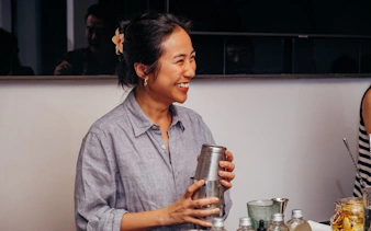 Person preparing coffee-themed cocktails in a Vietnamese setting.