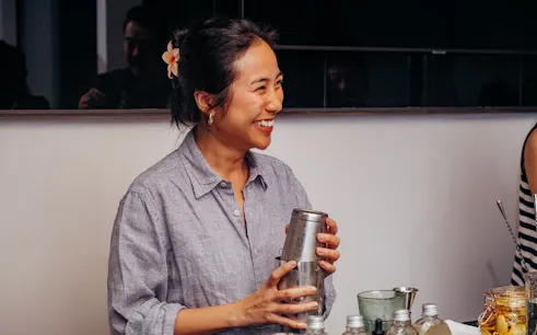 Person preparing coffee-themed cocktails in a Vietnamese setting.