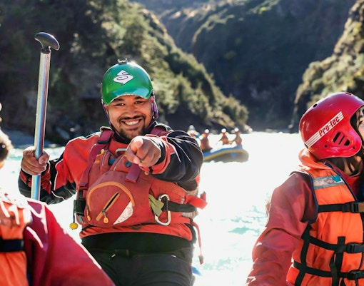 Whitewater rafters smiling on Shotover River, Queenstown adventure.