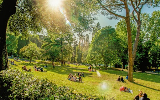 People enjoying a picnic on a sunny day at Villa Borghese, Rome.