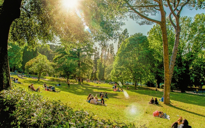 People enjoying a picnic on a sunny day at Villa Borghese, Rome.