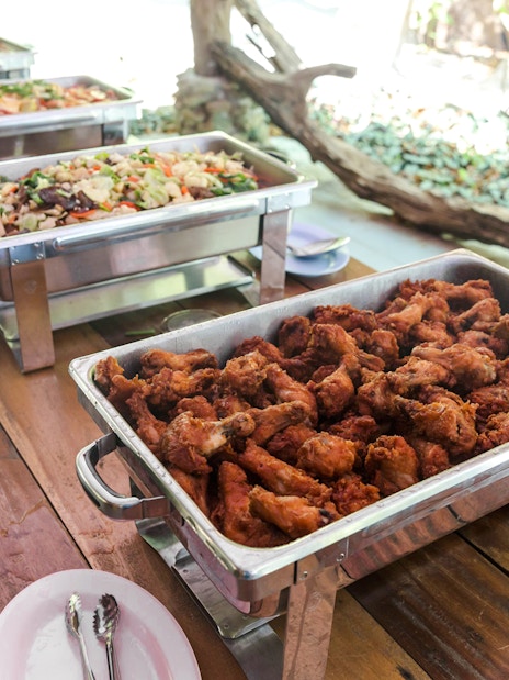 Buffet with fried chicken and assorted dishes on a wooden table.