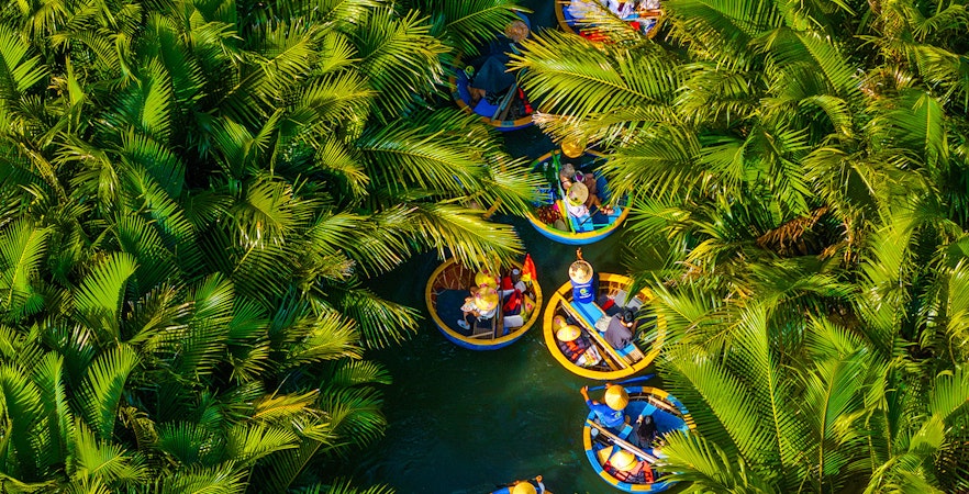 Aerial view of tourists in round basket boats navigating through lush coconut palms.