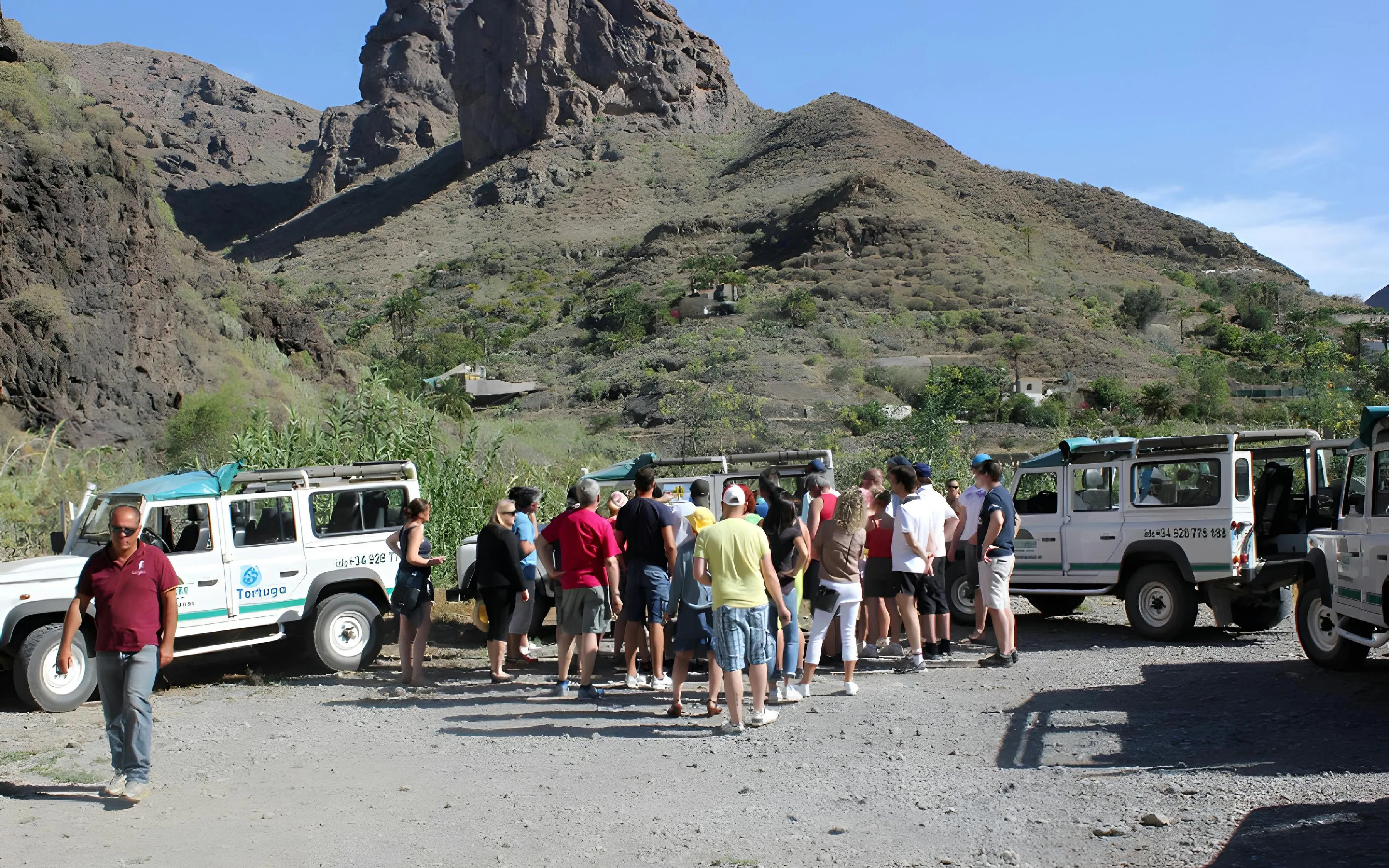 Tourists gather near 4x4 Jeeps on a mountainous off-road safari in the Canary Islands.