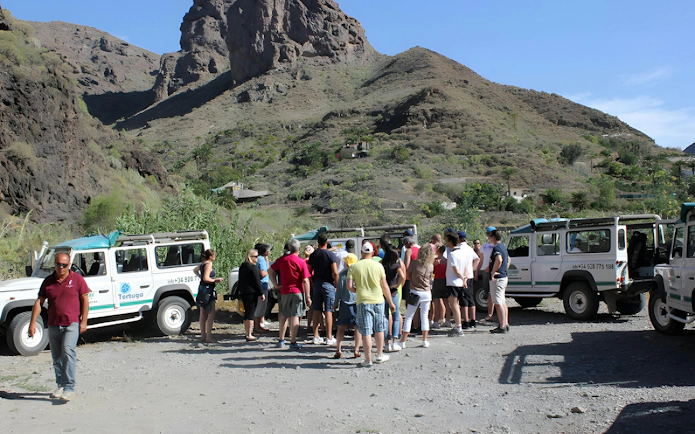 Tourists gather near 4x4 Jeeps on a mountainous off-road safari in the Canary Islands.