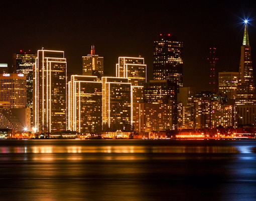 San Francisco skyline at night with illuminated buildings and Transamerica Pyramid.