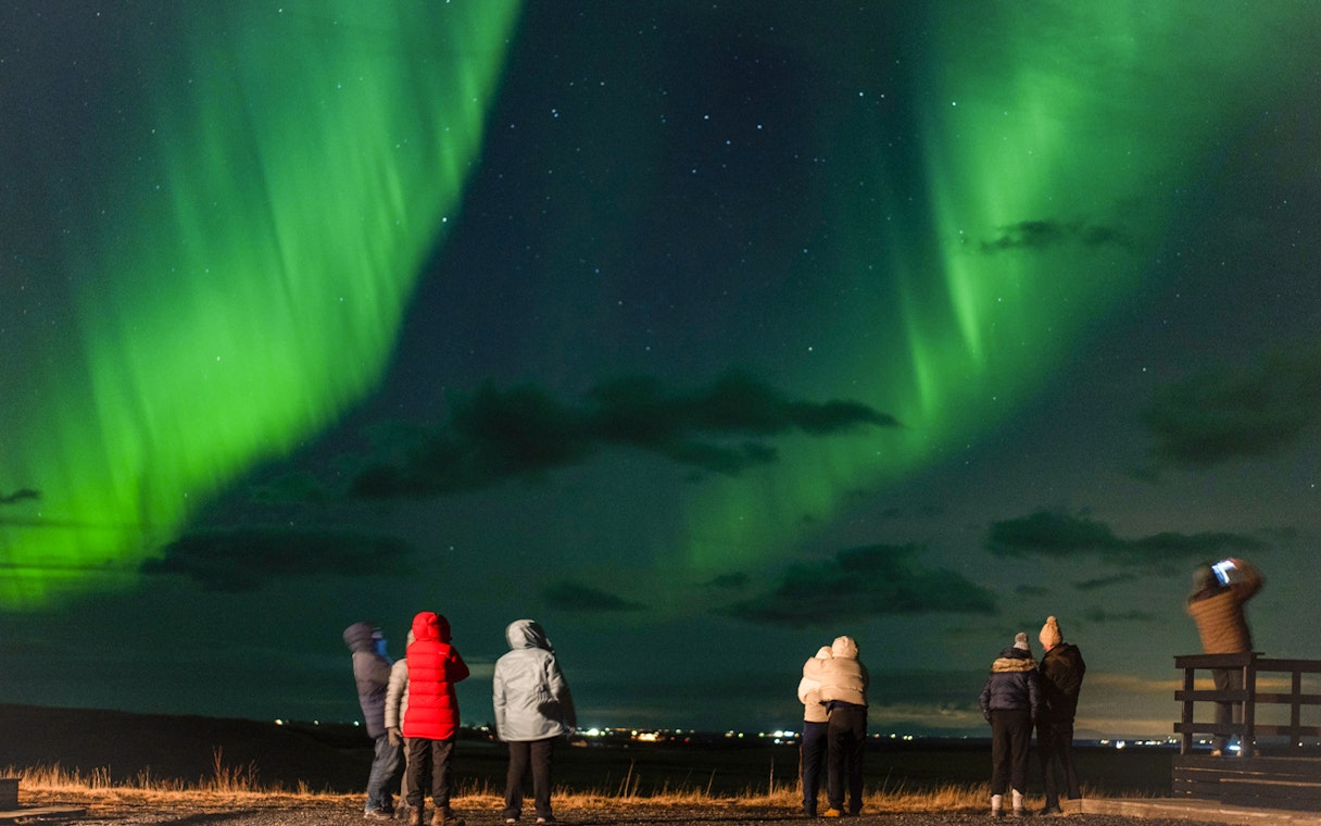 Small group watching Northern Lights on off-road tour with hot chocolate.