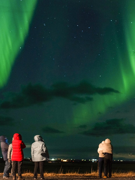 Small group watching Northern Lights on off-road tour with hot chocolate.