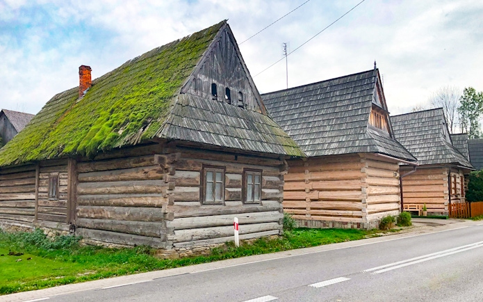 Traditional wooden houses in Zakopane along a road, part of the snowmobile tour with thermal baths.