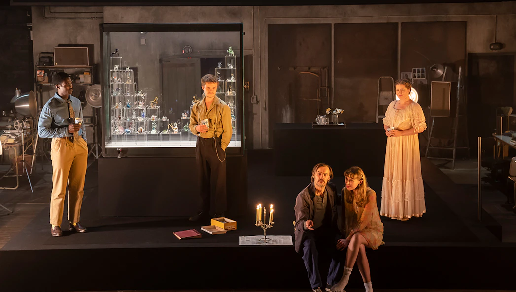Cast members of "The Glass Menagerie" on stage with a glass display case in the background.