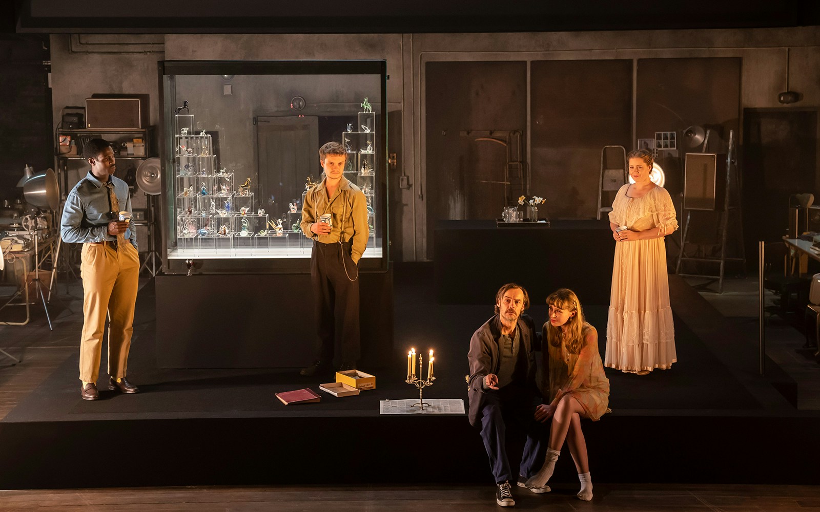 Cast members of "The Glass Menagerie" on stage with a glass display case in the background.