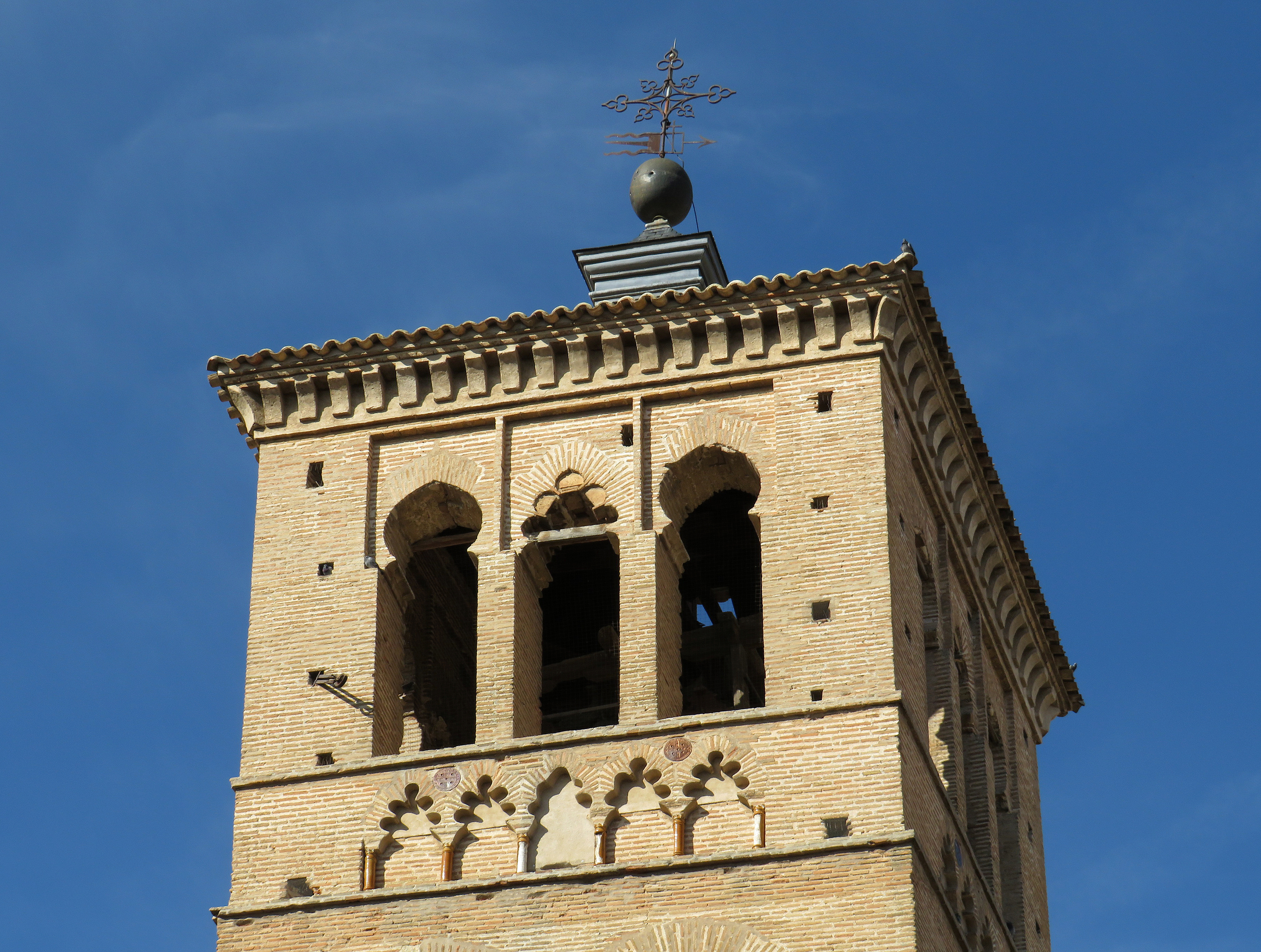 Church of Santo Tome bell tower with brick arches against blue sky in Toledo, Spain.