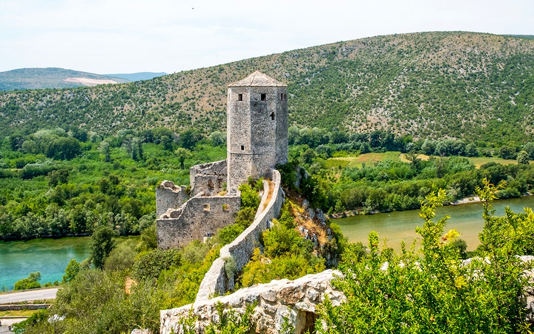 Pocitelj Citadel overlooking lush landscape and river in Bosnia and Herzegovina.