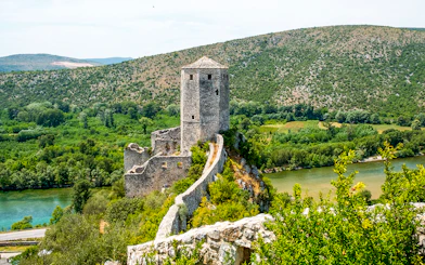 Pocitelj Citadel overlooking lush landscape and river in Bosnia and Herzegovina.