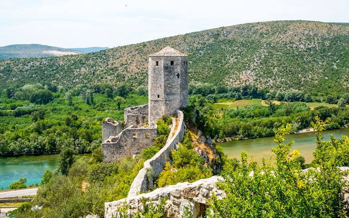 Pocitelj Citadel overlooking lush landscape and river in Bosnia and Herzegovina.