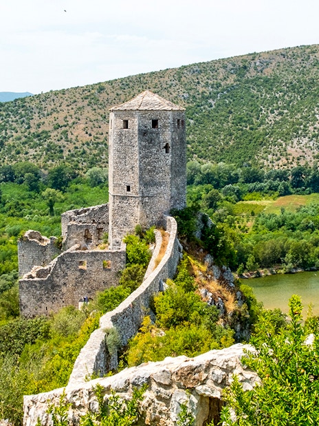 Pocitelj Citadel overlooking lush landscape and river in Bosnia and Herzegovina.