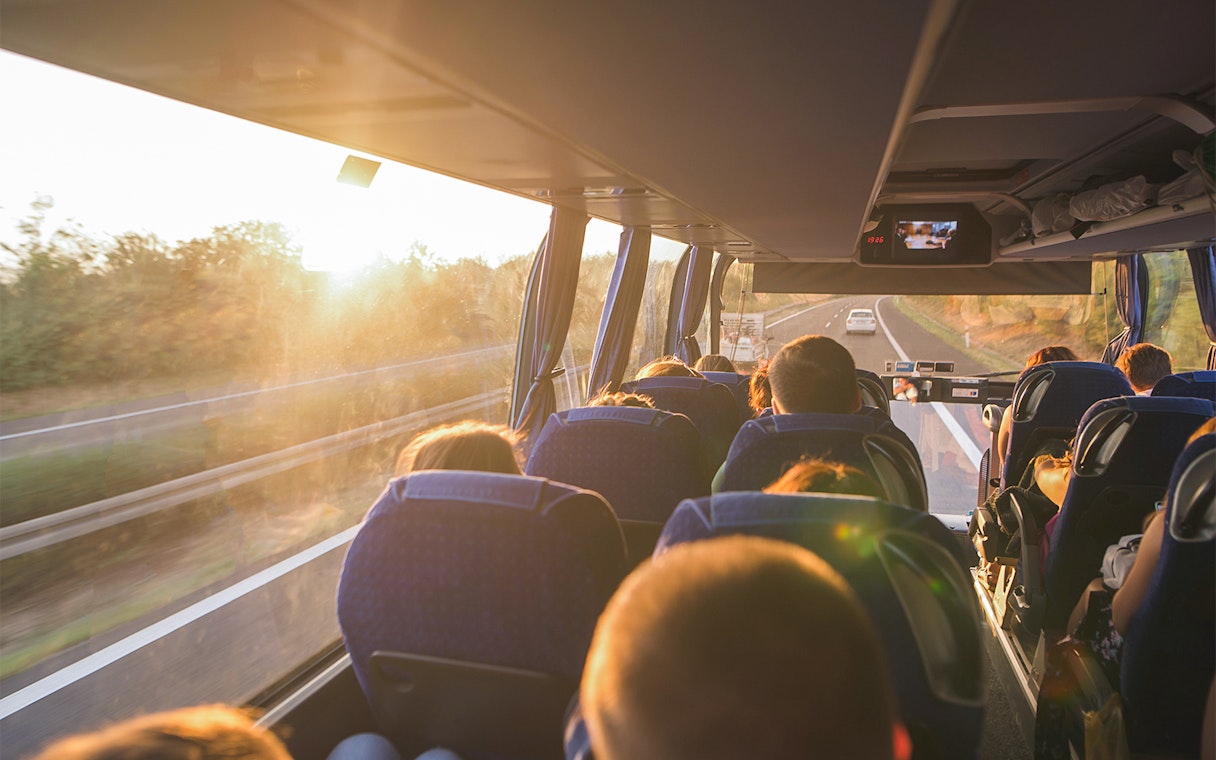 Passengers on a bus enjoying a scenic highway view at sunset, National Tickets Express.