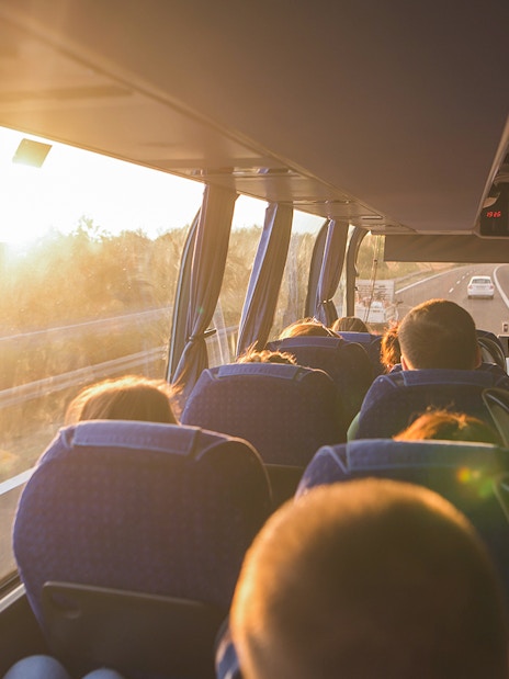 Passengers on a bus enjoying a scenic highway view at sunset, National Tickets Express.