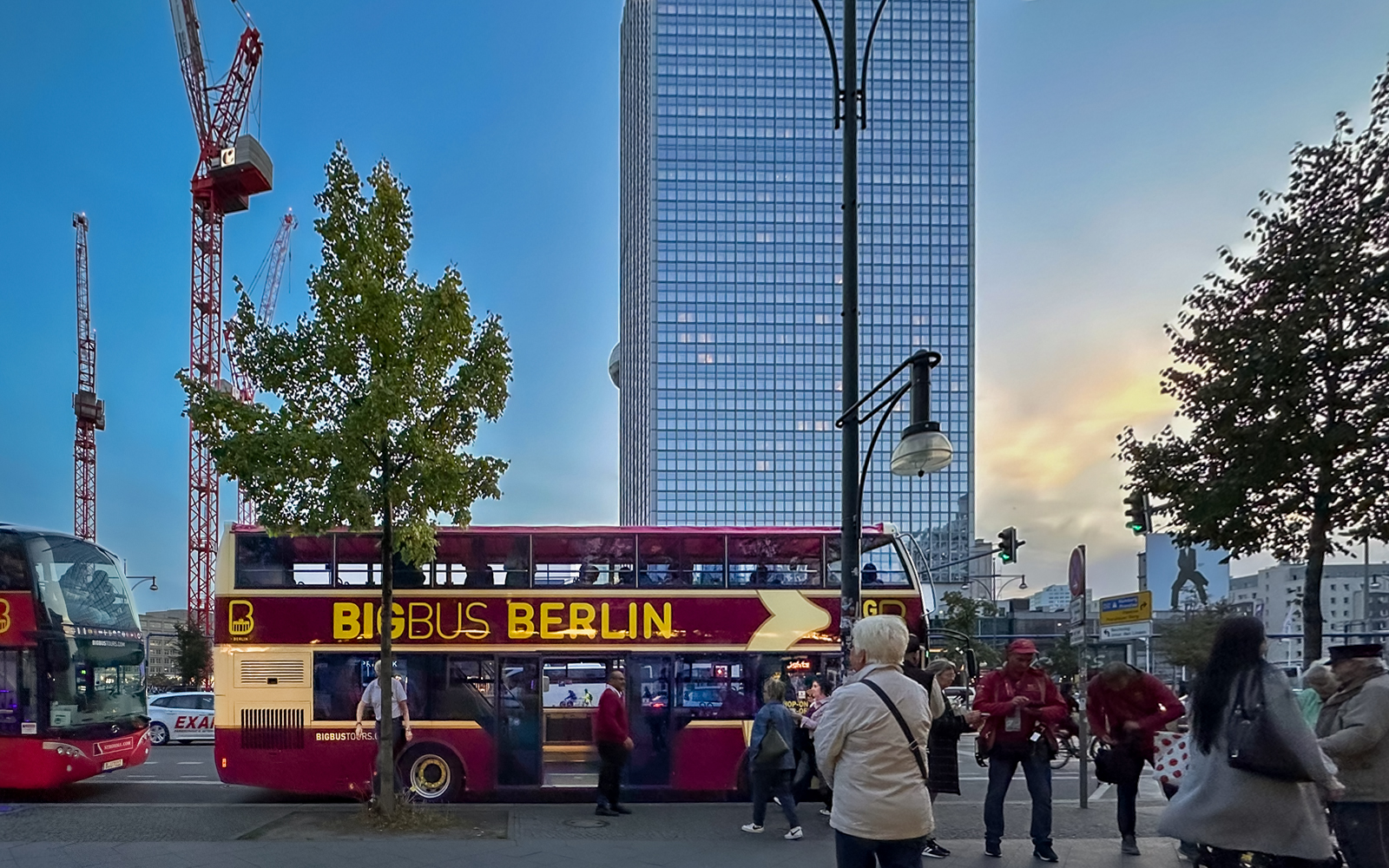 Berlin double-decker bus tour with cityscape and cranes in the background.