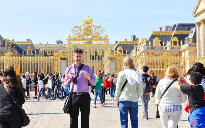 Tour group at the golden gates of the Palace of Versailles, France.