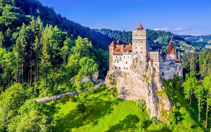 Bran Castle surrounded by lush green forest in Transylvania, Romania.