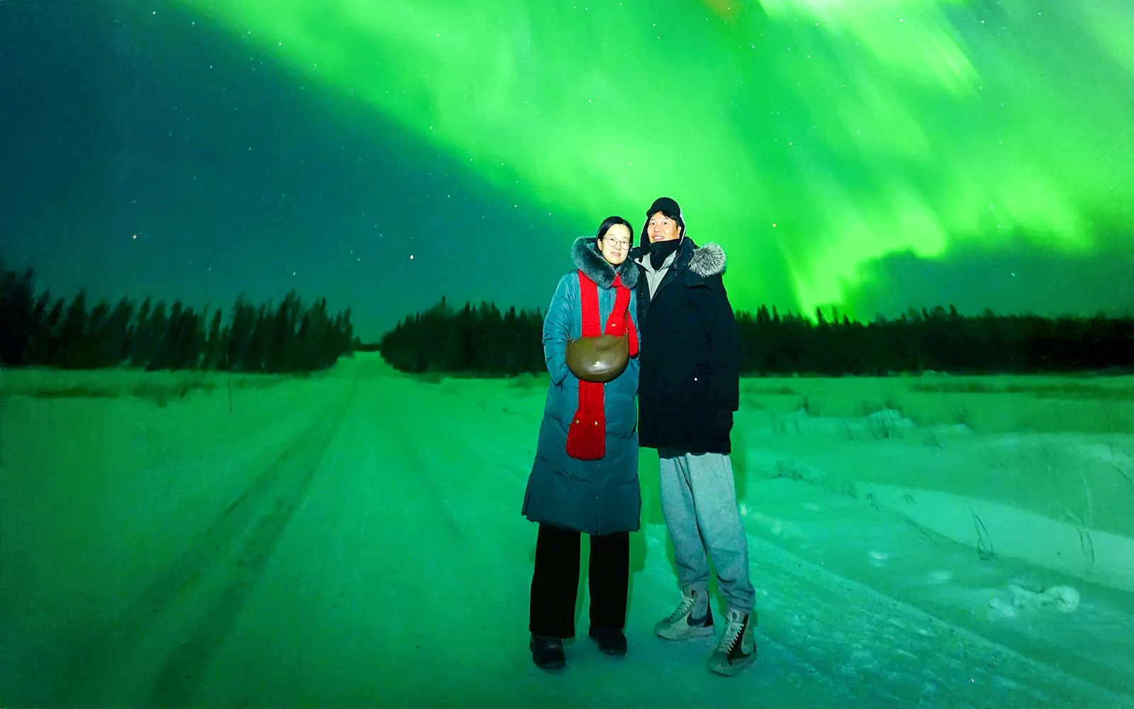 Guests on Northern Lights Chase Bus Tour in Rovaniemi under vibrant aurora borealis.