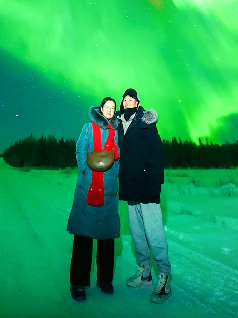 Guests on Northern Lights Chase Bus Tour in Rovaniemi under vibrant aurora borealis.