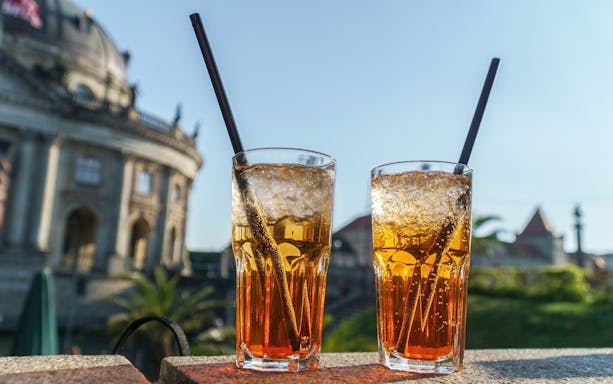 Two iced drinks with straws in front of Berlin's Bode Museum, QueerCityPass Berlin ABC.