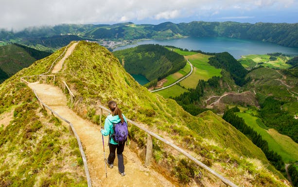 Hiker on trail overlooking Sete Cidades crater lakes in Azores.