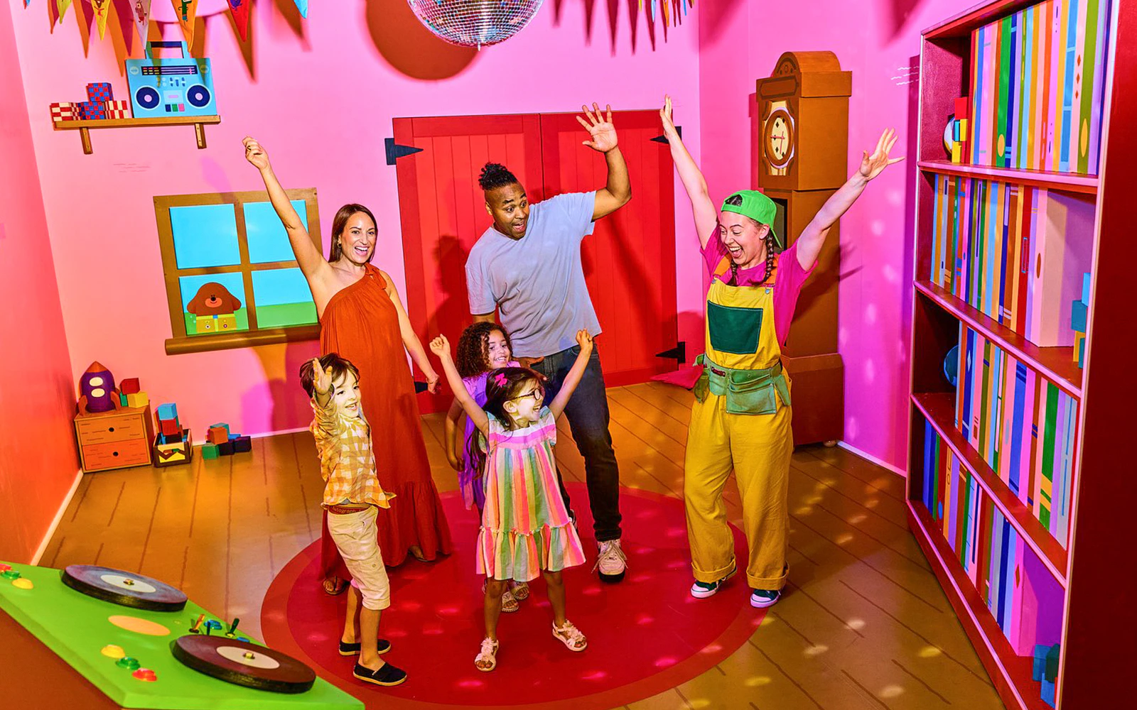 Children and adults enjoying CBeebies Rainbow Adventure in a colorful playroom.