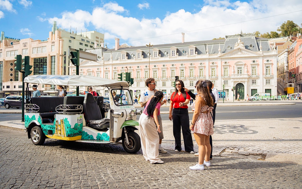 Tourists with guide at scenic Lisbon spot during eco tuk tuk tour.