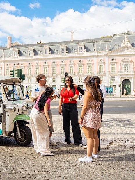 Tourists with guide at scenic Lisbon spot during eco tuk tuk tour.