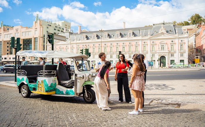 Tourists with guide at scenic Lisbon spot during eco tuk tuk tour.