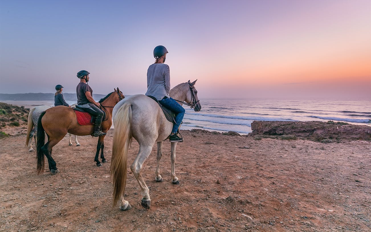 Horse riders overlooking the ocean at sunset on Carrapateira tour.