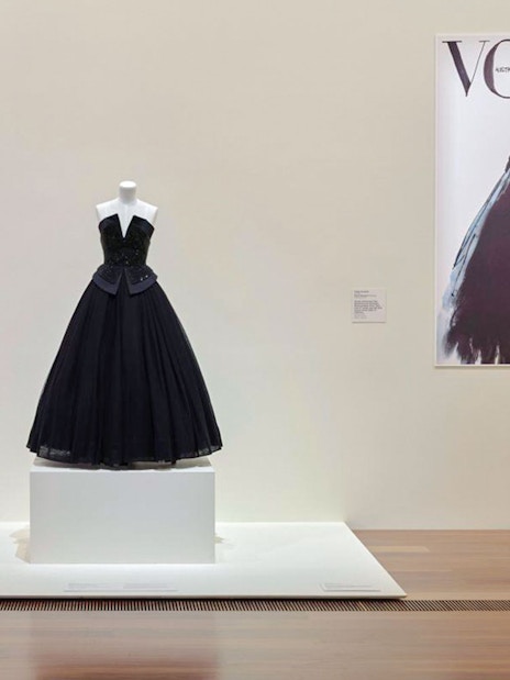 Mannequin displaying a black gown at Martin Grant Exhibition with Vogue cover in background.
