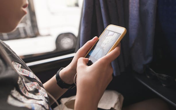 Person using smartphone on bus from Cancún Airport.