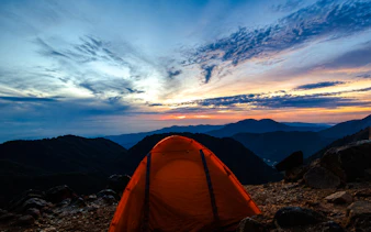 Orange tent at Sibayak Crater with sunrise over mountains, Medan.