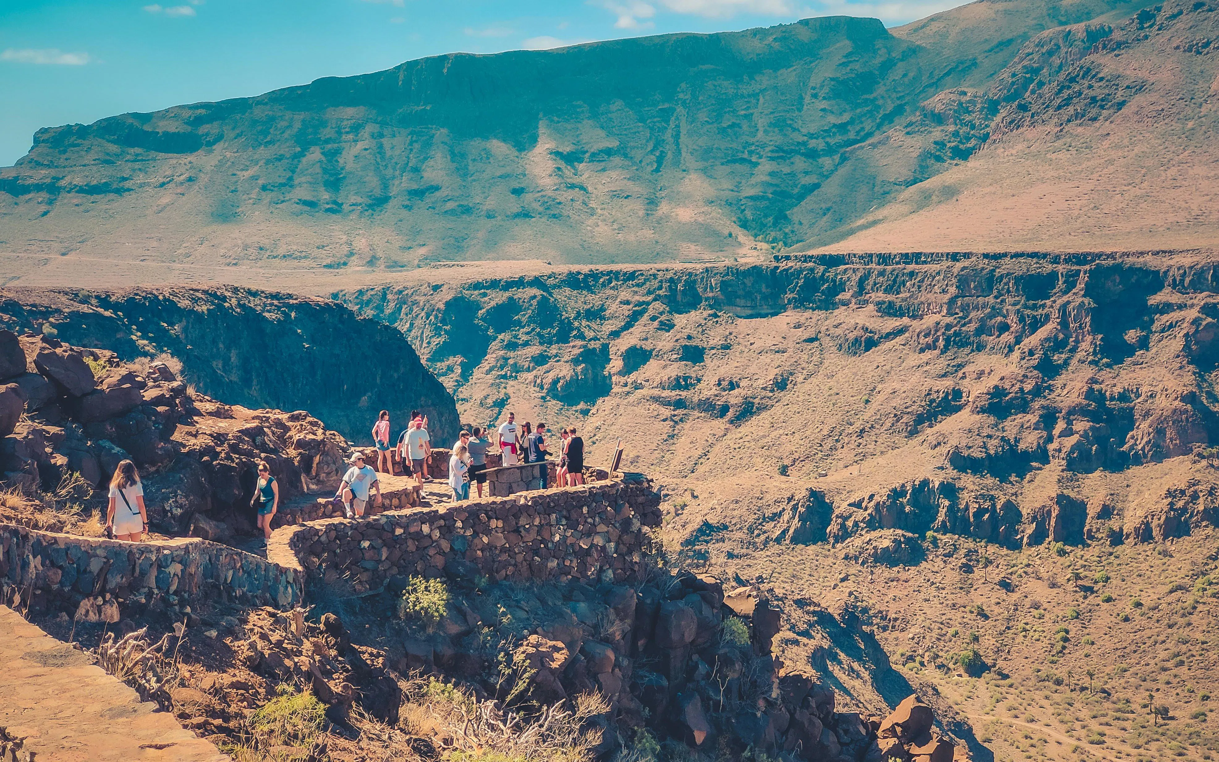 Visitors at Mirador El Guriete overlook volcanic landscape and ravines in Gran Canaria, Spain.