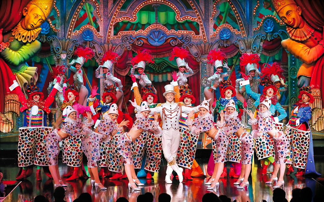 Performers in colorful costumes on stage at the Moulin Rouge Show Féerie, Paris.