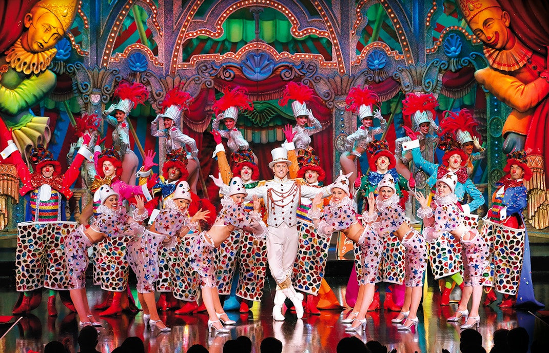 Performers in colorful costumes on stage at the Moulin Rouge Show Féerie, Paris.