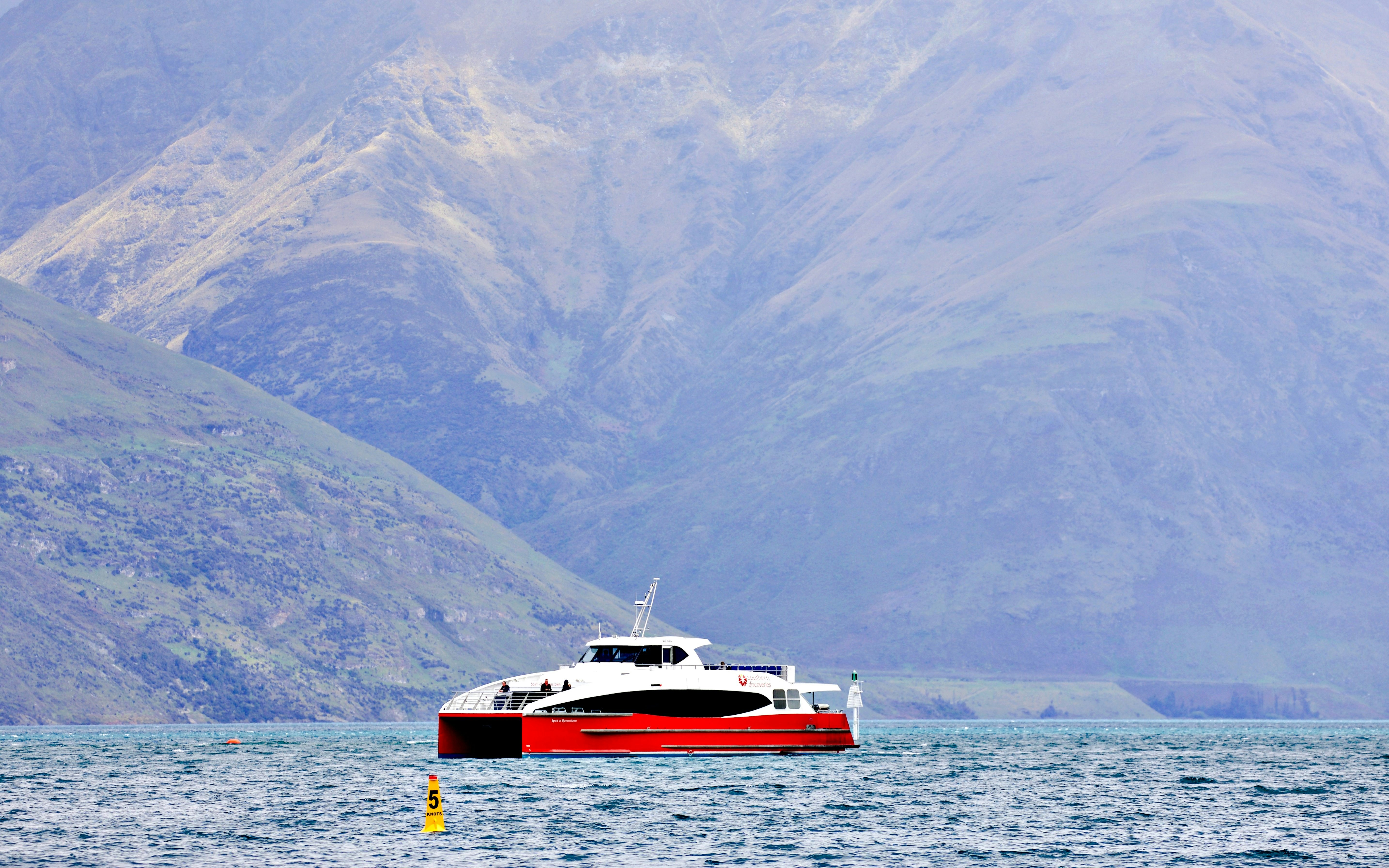 Catamaran on Lake Wakatipu during Spirit of Queenstown cruise with mountain backdrop.