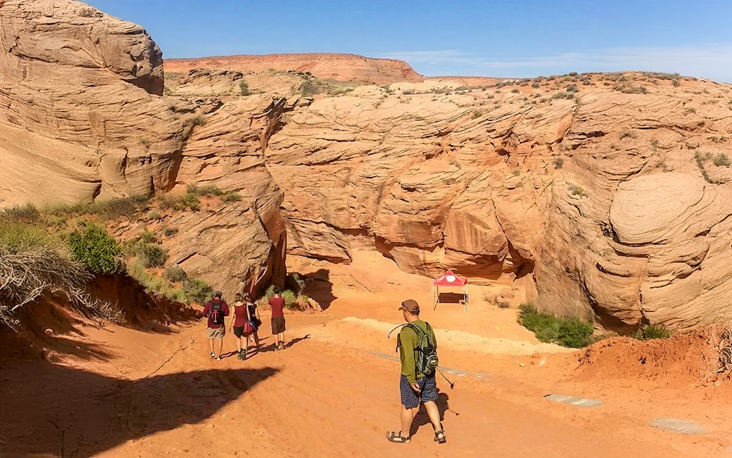 Visitors entering Antelope Canyon X, surrounded by red rock formations in Arizona.