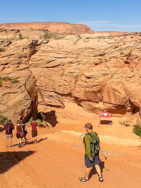 Visitors entering Antelope Canyon X, surrounded by red rock formations in Arizona.