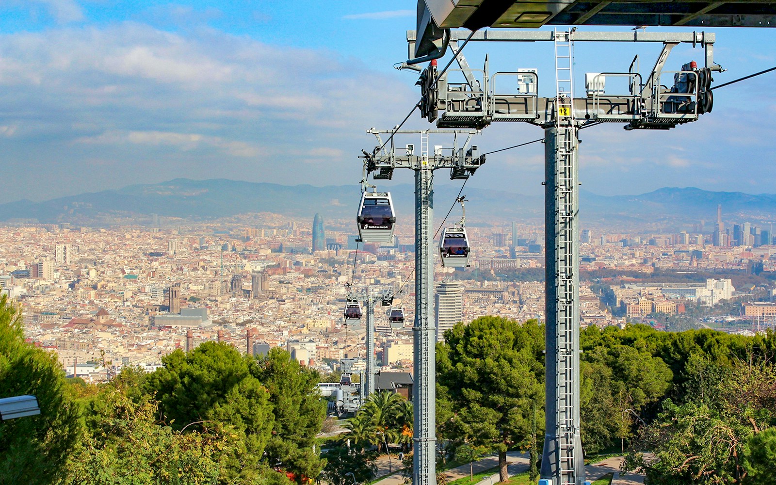 Cable car ascending Montjuic Hill with panoramic view of Barcelona cityscape.
