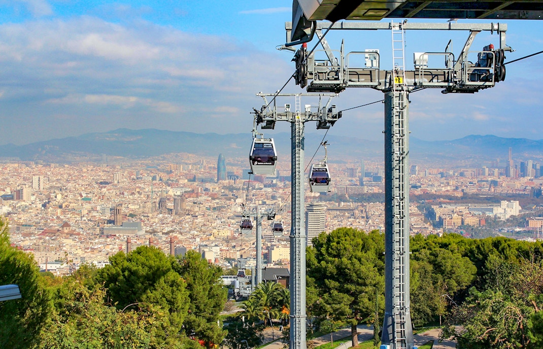 Cable car ascending Montjuic Hill with panoramic view of Barcelona cityscape.